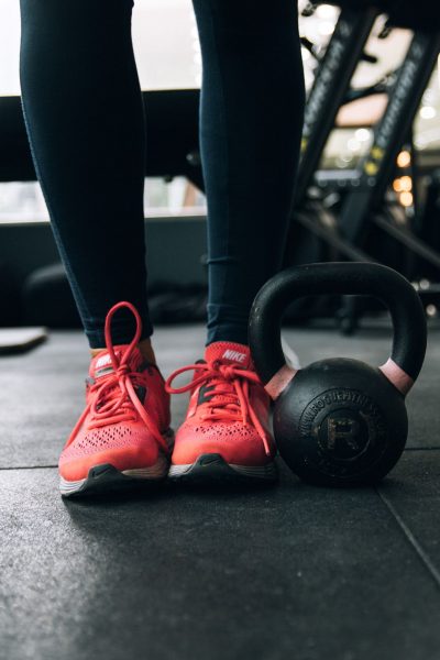 Close up of a person standing in the gym next to a kettlebell weight